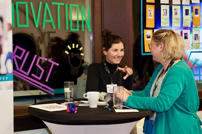 Zwei Personen unterhalten sich an einem Stehtisch stehend